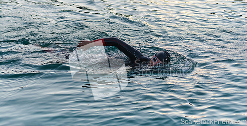 Image of A professional triathlete trains with unwavering dedication for an upcoming competition at a lake, emanating a sense of athleticism and profound commitment to excellence.