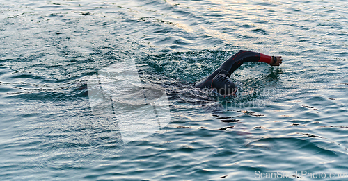 Image of A professional triathlete trains with unwavering dedication for an upcoming competition at a lake, emanating a sense of athleticism and profound commitment to excellence.