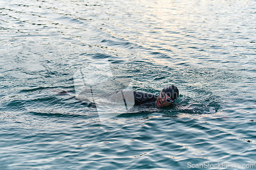 Image of A professional triathlete trains with unwavering dedication for an upcoming competition at a lake, emanating a sense of athleticism and profound commitment to excellence.