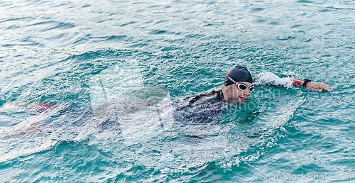 Image of A professional triathlete trains with unwavering dedication for an upcoming competition at a lake, emanating a sense of athleticism and profound commitment to excellence.