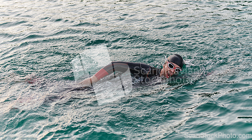 Image of A professional triathlete trains with unwavering dedication for an upcoming competition at a lake, emanating a sense of athleticism and profound commitment to excellence.