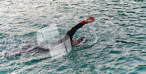 Image of A professional triathlete trains with unwavering dedication for an upcoming competition at a lake, emanating a sense of athleticism and profound commitment to excellence.