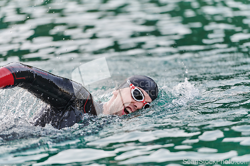 Image of A professional triathlete trains with unwavering dedication for an upcoming competition at a lake, emanating a sense of athleticism and profound commitment to excellence.