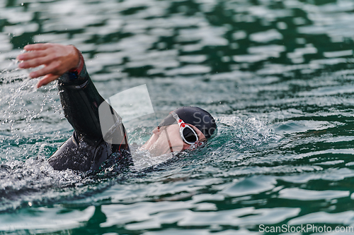 Image of A professional triathlete trains with unwavering dedication for an upcoming competition at a lake, emanating a sense of athleticism and profound commitment to excellence.