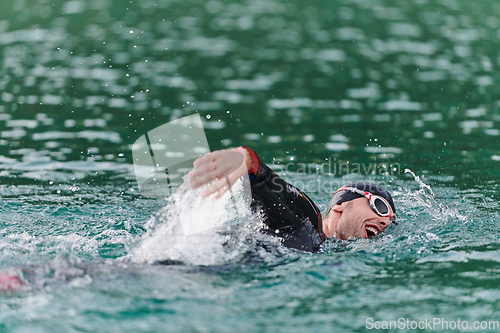 Image of A professional triathlete trains with unwavering dedication for an upcoming competition at a lake, emanating a sense of athleticism and profound commitment to excellence.