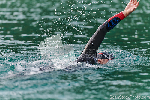 Image of A professional triathlete trains with unwavering dedication for an upcoming competition at a lake, emanating a sense of athleticism and profound commitment to excellence.