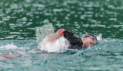 Image of A professional triathlete trains with unwavering dedication for an upcoming competition at a lake, emanating a sense of athleticism and profound commitment to excellence.