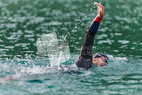 Image of A professional triathlete trains with unwavering dedication for an upcoming competition at a lake, emanating a sense of athleticism and profound commitment to excellence.