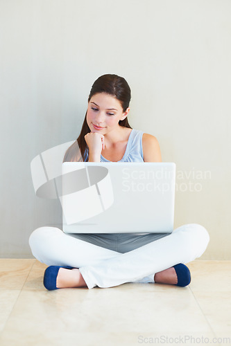 Image of Woman, laptop and thinking for idea, decision or choice sitting against a wall at home. Female person freelancer in wonder, thought or planning for online research or communication on floor at house