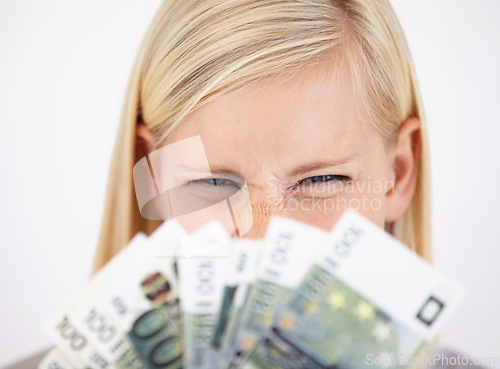 Image of Money, finance and lottery winner with a woman closeup in studio on a white background for profit or increase. Eyes, economy or investment and an excited young person with cash for financial freedom