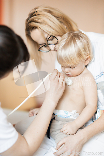 Image of Small child being checked for heart murmur by heart ultrasound exam by cardiologist as part of regular medical checkout at pediatrician.