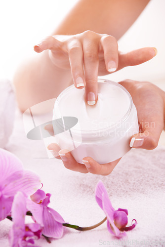 Image of Woman, hands and flowers with cream for skincare, cosmetics or beauty products in salon or spa treatment. Closeup of female person with jar or container of lotion, SPF or creme for skin moisturizer