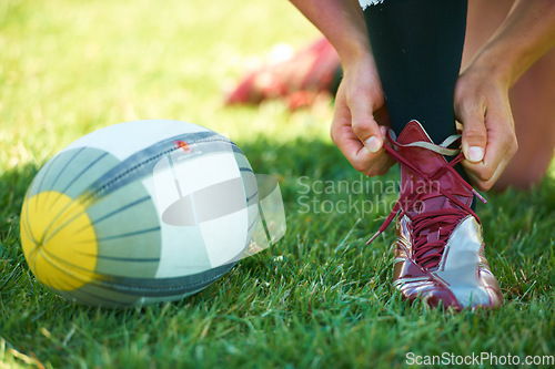 Image of Rugby, ball and hands with shoes of person on field for training, practice and challenge. Health, start and games with closeup of sports athlete tying laces on outdoor pitch for stadium and fitness