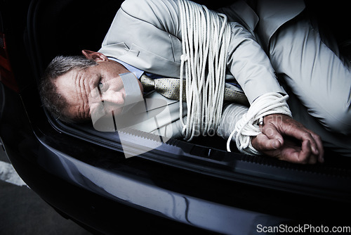 Image of Car boot, crime and portrait of business man with tape, rope and kidnap danger in parking lot. Fear, stress and face of male victim in a vehicle trunk with anxiety, horror or panic, scared or ransom