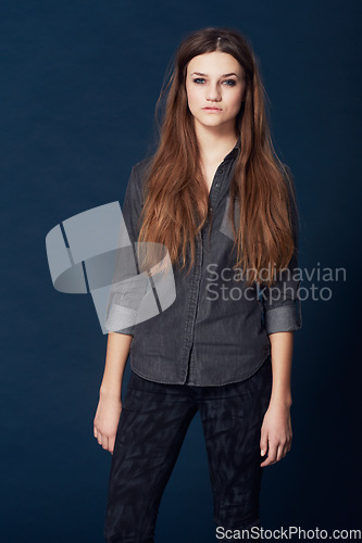 Image of Woman, portrait and attitude for cool fashion in studio or stylish clothing, confident and serious by blue background. Female model person and tough face, beauty and trendy or relax in Sweden