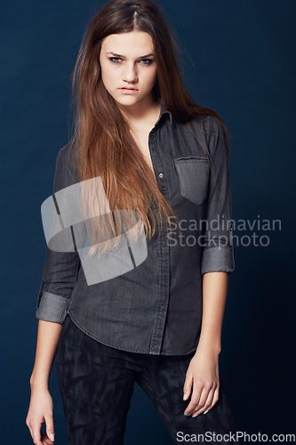 Image of Woman, portrait and attitude for fashion in studio or cool clothing, confidence and fierce by blue background. Female model person, mean and tough on face, beauty and trendy or edgy makeup in Sweden