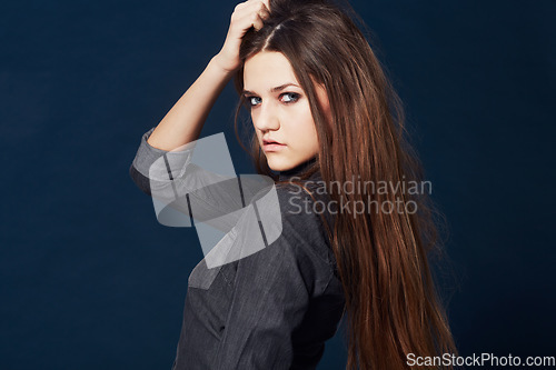 Image of Woman, portrait and attitude or confidence in studio or cool clothing, fashion and fierce by blue background. Female model person, mean and tough on face, beauty and trendy or edgy makeup in Sweden
