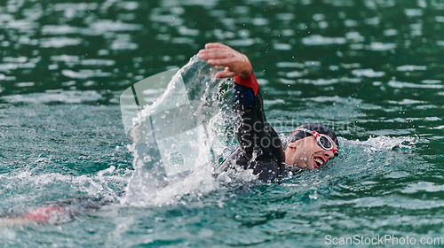 Image of A professional triathlete trains with unwavering dedication for an upcoming competition at a lake, emanating a sense of athleticism and profound commitment to excellence.