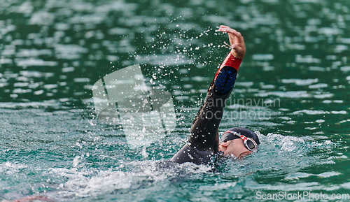 Image of A professional triathlete trains with unwavering dedication for an upcoming competition at a lake, emanating a sense of athleticism and profound commitment to excellence.