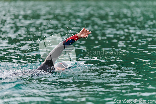 Image of A professional triathlete trains with unwavering dedication for an upcoming competition at a lake, emanating a sense of athleticism and profound commitment to excellence.