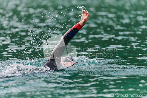 Image of A professional triathlete trains with unwavering dedication for an upcoming competition at a lake, emanating a sense of athleticism and profound commitment to excellence.