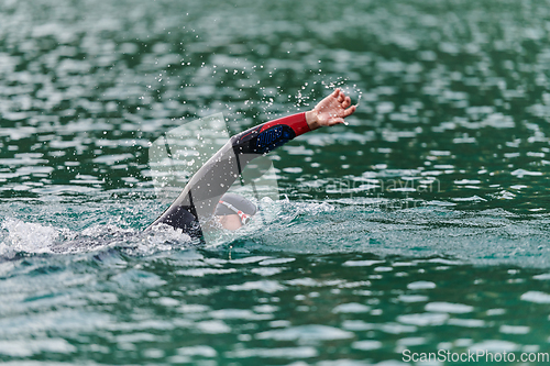 Image of A professional triathlete trains with unwavering dedication for an upcoming competition at a lake, emanating a sense of athleticism and profound commitment to excellence.