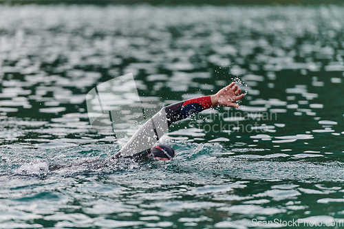 Image of A professional triathlete trains with unwavering dedication for an upcoming competition at a lake, emanating a sense of athleticism and profound commitment to excellence.