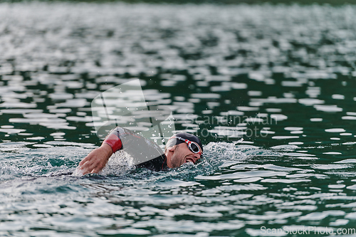 Image of A professional triathlete trains with unwavering dedication for an upcoming competition at a lake, emanating a sense of athleticism and profound commitment to excellence.