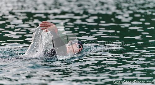 Image of A professional triathlete trains with unwavering dedication for an upcoming competition at a lake, emanating a sense of athleticism and profound commitment to excellence.