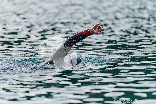 Image of A professional triathlete trains with unwavering dedication for an upcoming competition at a lake, emanating a sense of athleticism and profound commitment to excellence.