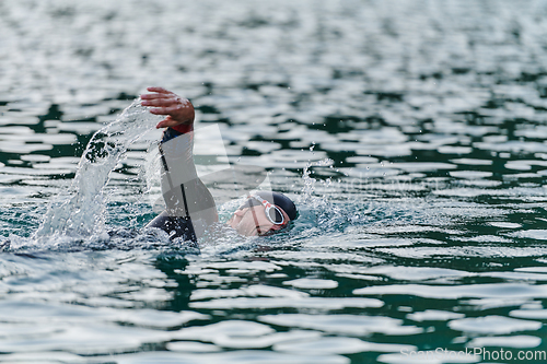 Image of A professional triathlete trains with unwavering dedication for an upcoming competition at a lake, emanating a sense of athleticism and profound commitment to excellence.