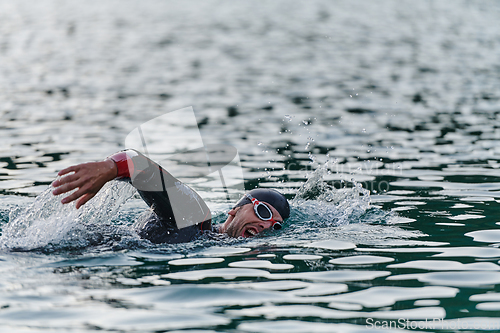 Image of A professional triathlete trains with unwavering dedication for an upcoming competition at a lake, emanating a sense of athleticism and profound commitment to excellence.