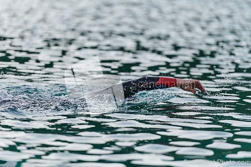 Image of A professional triathlete trains with unwavering dedication for an upcoming competition at a lake, emanating a sense of athleticism and profound commitment to excellence.