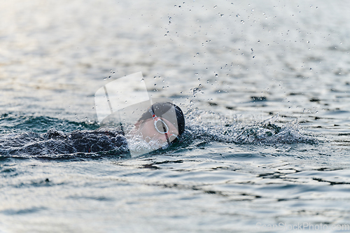 Image of A professional triathlete trains with unwavering dedication for an upcoming competition at a lake, emanating a sense of athleticism and profound commitment to excellence.