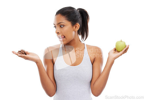 Image of Woman, apple and chocolate in studio with diet risk, temptation and cheat day with healthy food choice or sugar in studio. Person with sweets versus green fruit in palm or detox on a white background