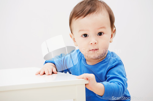 Image of Baby, portrait and balance for walking steps in home for childhood development, safety or mockup space. Boy, kid and face or holding furniture for growing support or progress, learning or curious