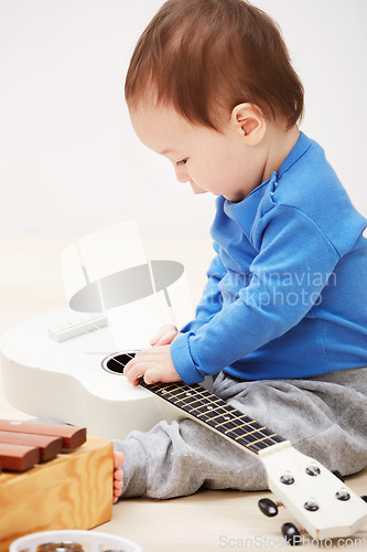 Image of Baby, guitar toys and play in home for entertainment joy, childhood development or education. Boy, kid and instruments for musical strings for song learning in apartment or growing, progress or games