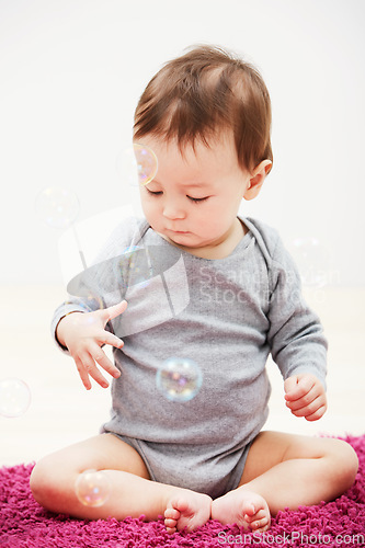 Image of Baby, bubbles and playing game in home for childhood development, curious wondering or education. Kid, growth toys and mockup space or learning progress for sensory, coordination or entertainment