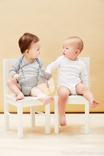 Image of Kids, chair and baby boys for growth or child development in studio on an orange background. Youth, cute or adorable and sibling or little infant children sitting together for family bonding