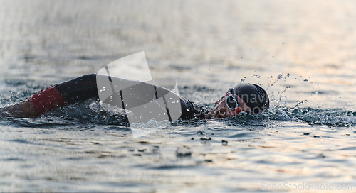 Image of A professional triathlete trains with unwavering dedication for an upcoming competition at a lake, emanating a sense of athleticism and profound commitment to excellence.