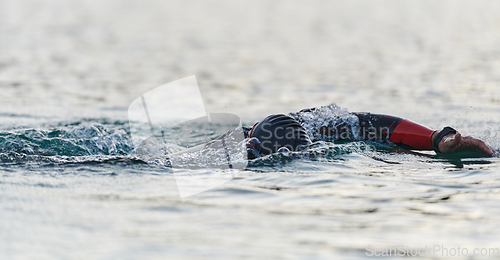 Image of A professional triathlete trains with unwavering dedication for an upcoming competition at a lake, emanating a sense of athleticism and profound commitment to excellence.