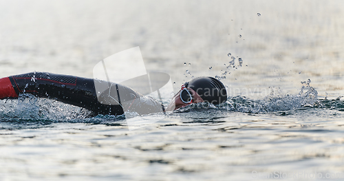 Image of A professional triathlete trains with unwavering dedication for an upcoming competition at a lake, emanating a sense of athleticism and profound commitment to excellence.