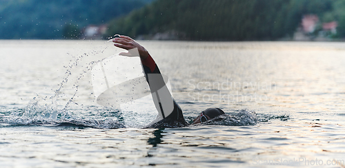 Image of A professional triathlete trains with unwavering dedication for an upcoming competition at a lake, emanating a sense of athleticism and profound commitment to excellence.