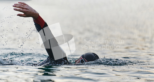 Image of A professional triathlete trains with unwavering dedication for an upcoming competition at a lake, emanating a sense of athleticism and profound commitment to excellence.