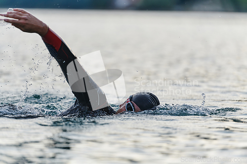 Image of A professional triathlete trains with unwavering dedication for an upcoming competition at a lake, emanating a sense of athleticism and profound commitment to excellence.