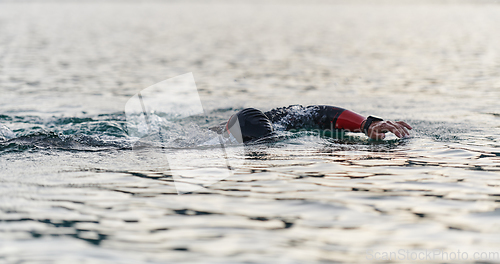 Image of A professional triathlete trains with unwavering dedication for an upcoming competition at a lake, emanating a sense of athleticism and profound commitment to excellence.