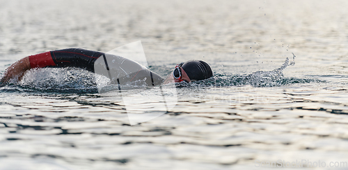 Image of A professional triathlete trains with unwavering dedication for an upcoming competition at a lake, emanating a sense of athleticism and profound commitment to excellence.