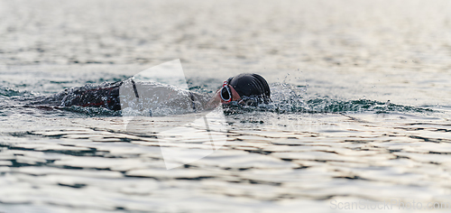 Image of A professional triathlete trains with unwavering dedication for an upcoming competition at a lake, emanating a sense of athleticism and profound commitment to excellence.