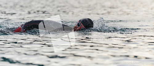 Image of A professional triathlete trains with unwavering dedication for an upcoming competition at a lake, emanating a sense of athleticism and profound commitment to excellence.