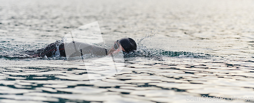 Image of A professional triathlete trains with unwavering dedication for an upcoming competition at a lake, emanating a sense of athleticism and profound commitment to excellence.